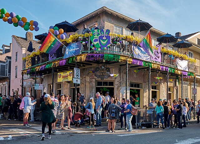 Image of the French Quarter during Pride. The iron work balconies are covered in rainbow flags and beads. 